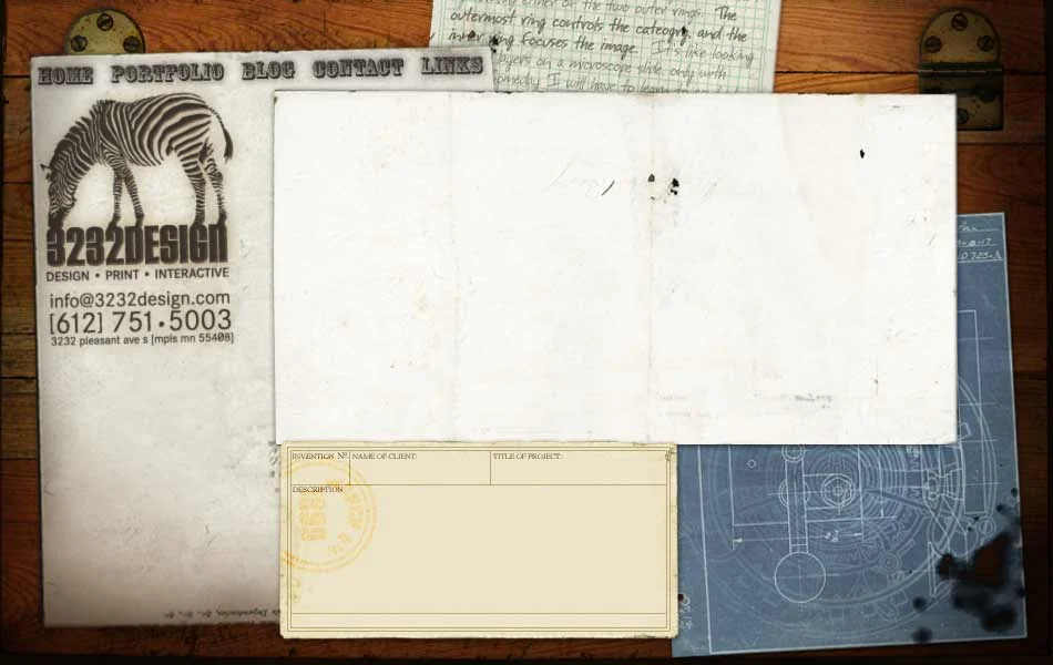 The 3232 Design workbench: parchment, a zebra card, blueprints and a note on old wood.